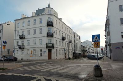 ulica Środkowa, na rogu biała kamienica, zachód słońca